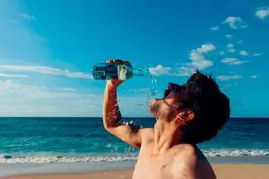 ¿Cuánta agua debo tomar por día? 7 cuánta agua debo tomar Hombre sediento tomado agua en la playa